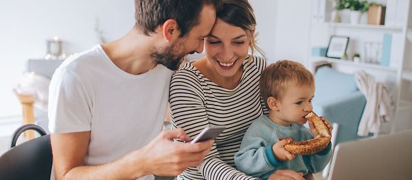 Junge Familie in einer Wohnung am Tisch mit einem Laptop