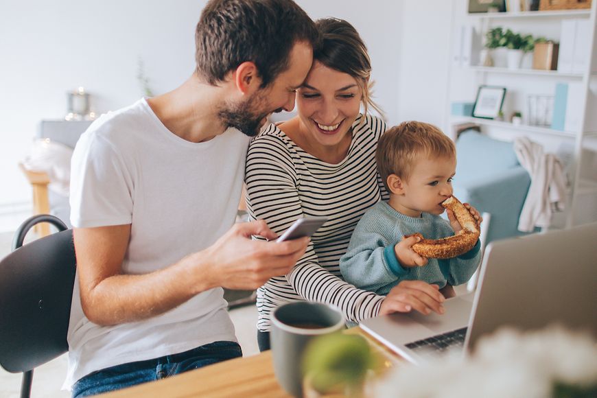 Junge Familie in einer Wohnung am Tisch mit einem Laptop