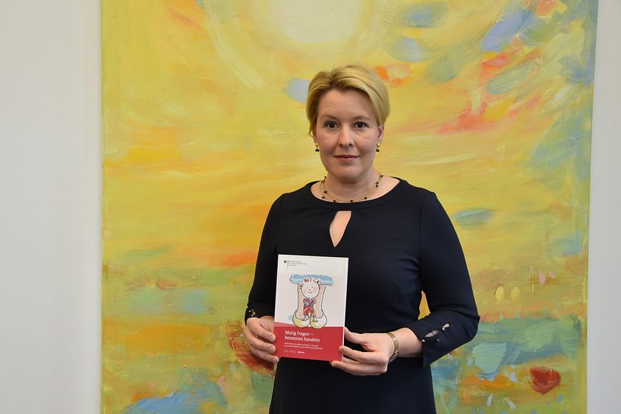 Dr. Franziska Giffey hält die Broschüre "Mutig fragen - besonnen handeln" in den Händen 