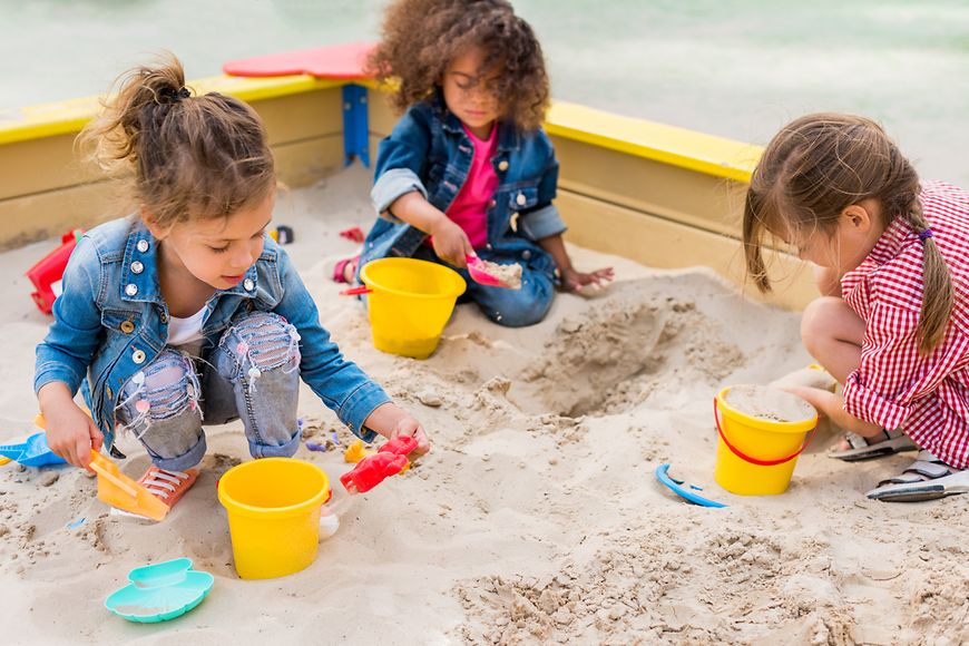 Drei Mädchen spielen im Sandkasten