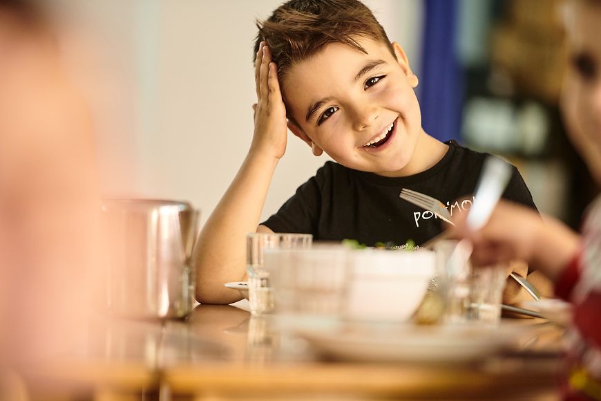 Ein Kind sitzt lachend an einem Esstisch