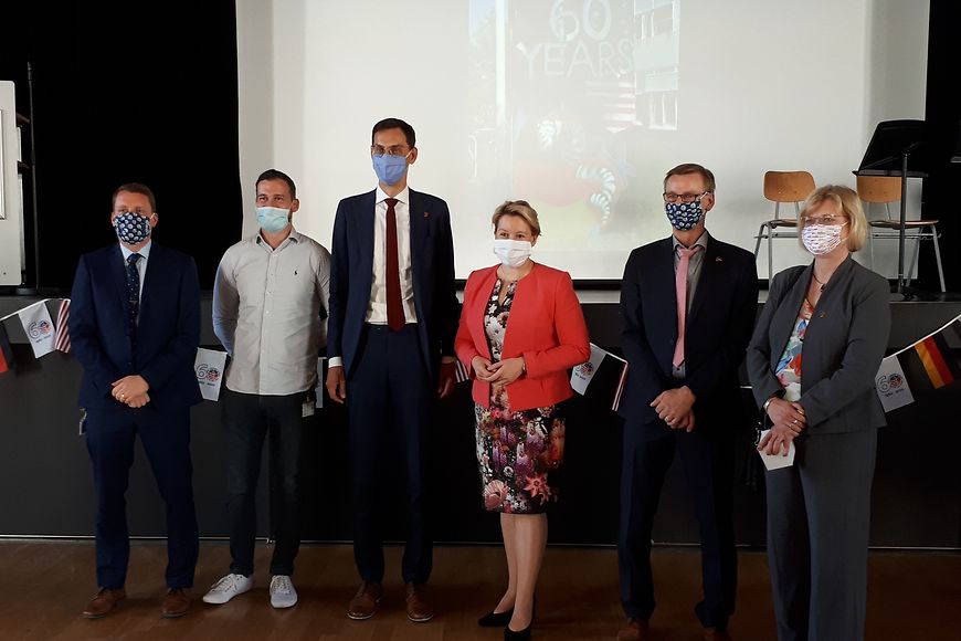 Bundesfamilienministerin Dr. Franziska Giffey und weitere Personen in der John-F-Kennedy-Schule, vor einem Bild: 60 Years.