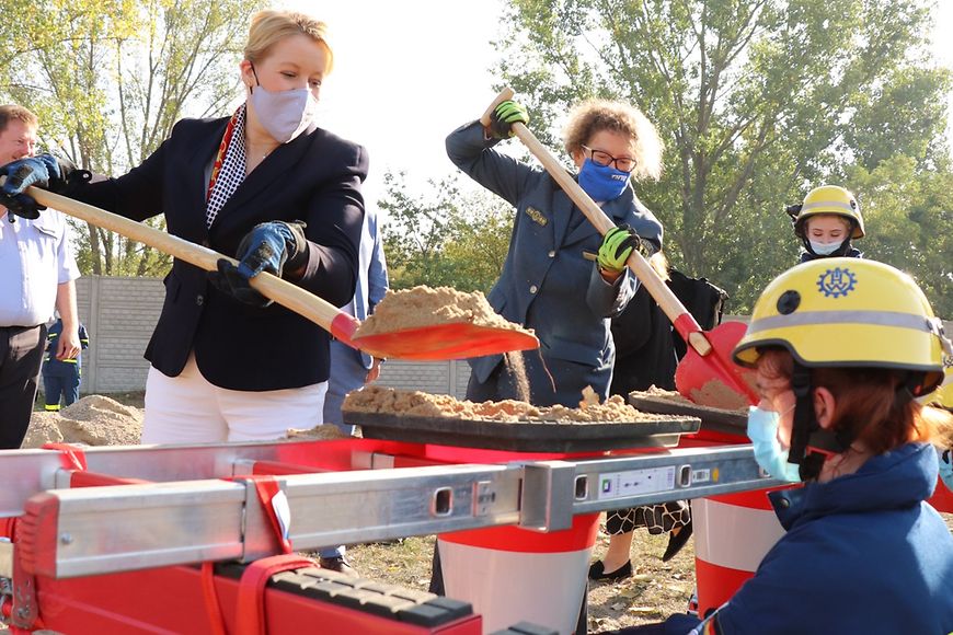 Bundesfamilienministerin Dr. Franziska Giffey im THW-Ausbildungszentrum in Brandenburg mit einer Schaufel Sand in den Händen