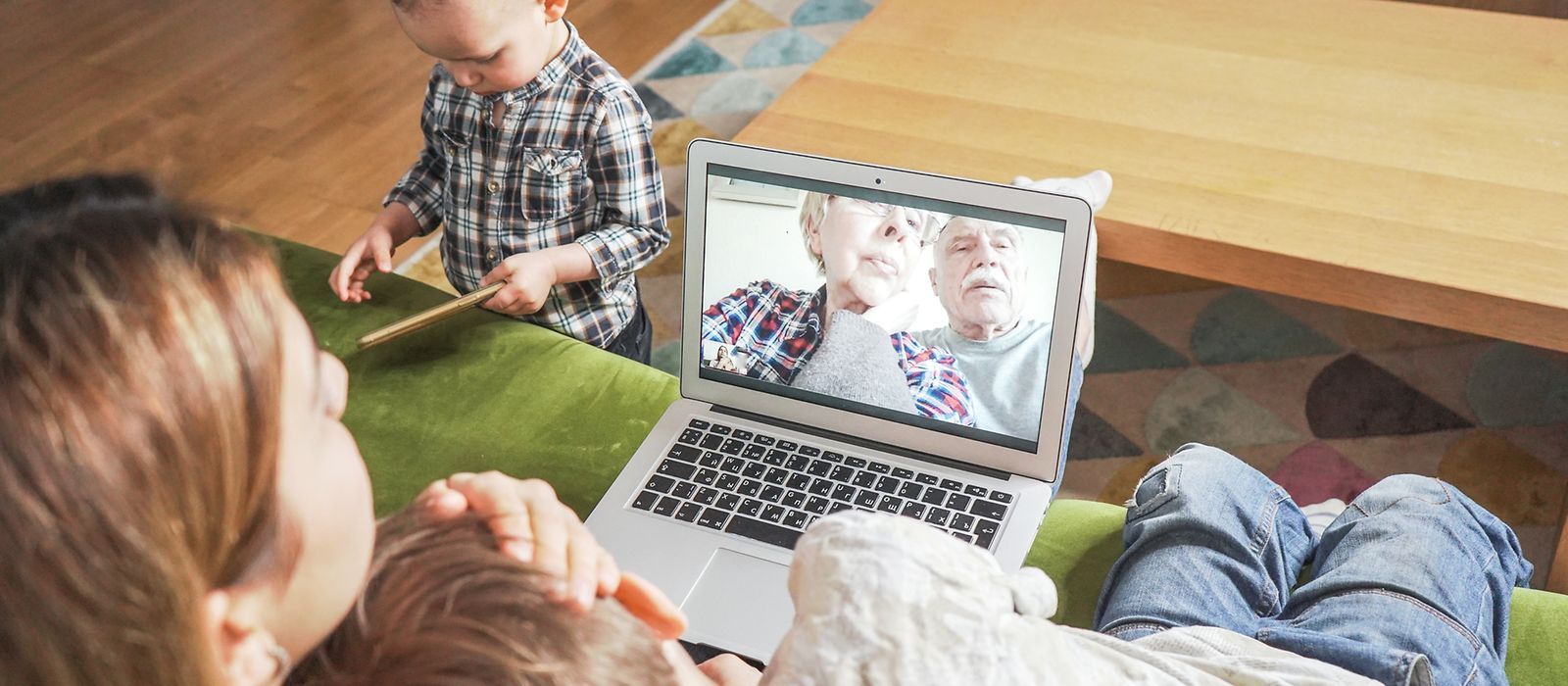 Eine Frau und ihren beiden Kinder sprechen online mit einem älteren Paar