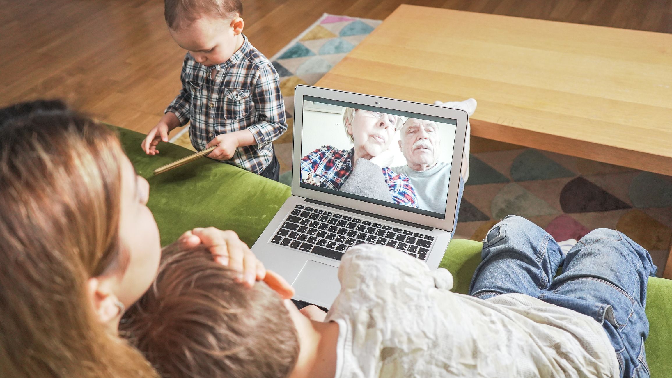 Eine Frau und ihren beiden Kinder sprechen online mit einem älteren Paar