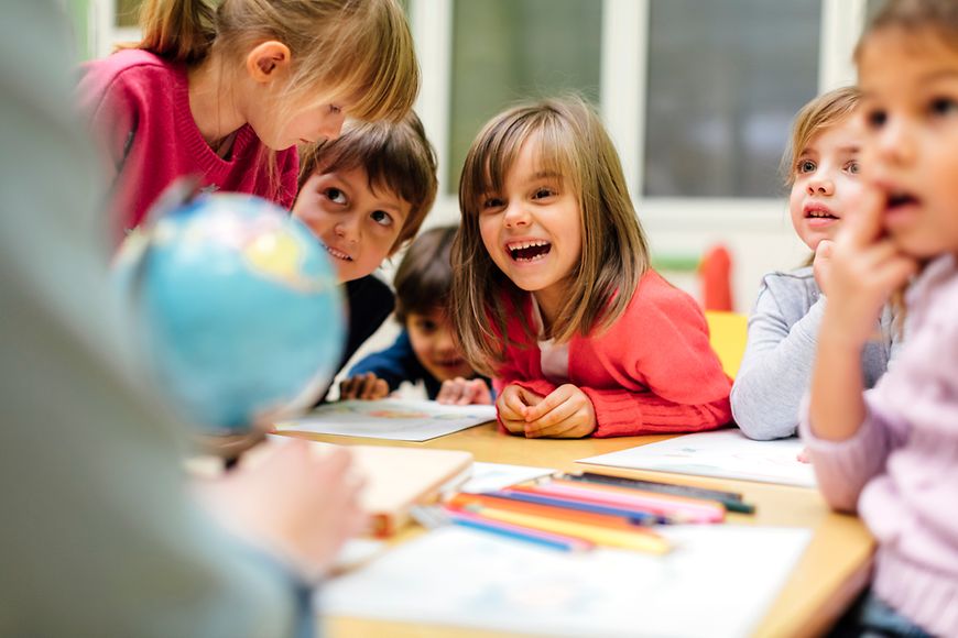 Kinder in einen Raum mit Schreibmaterialien an einem Tisch