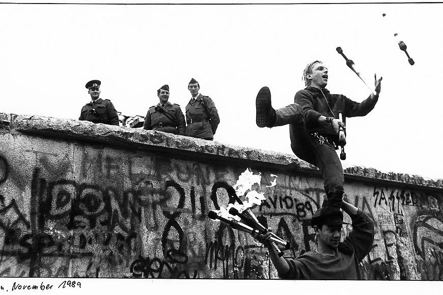 Schwarzweiß-Foto eines jungen Mannes, der an der Mauer jongliert