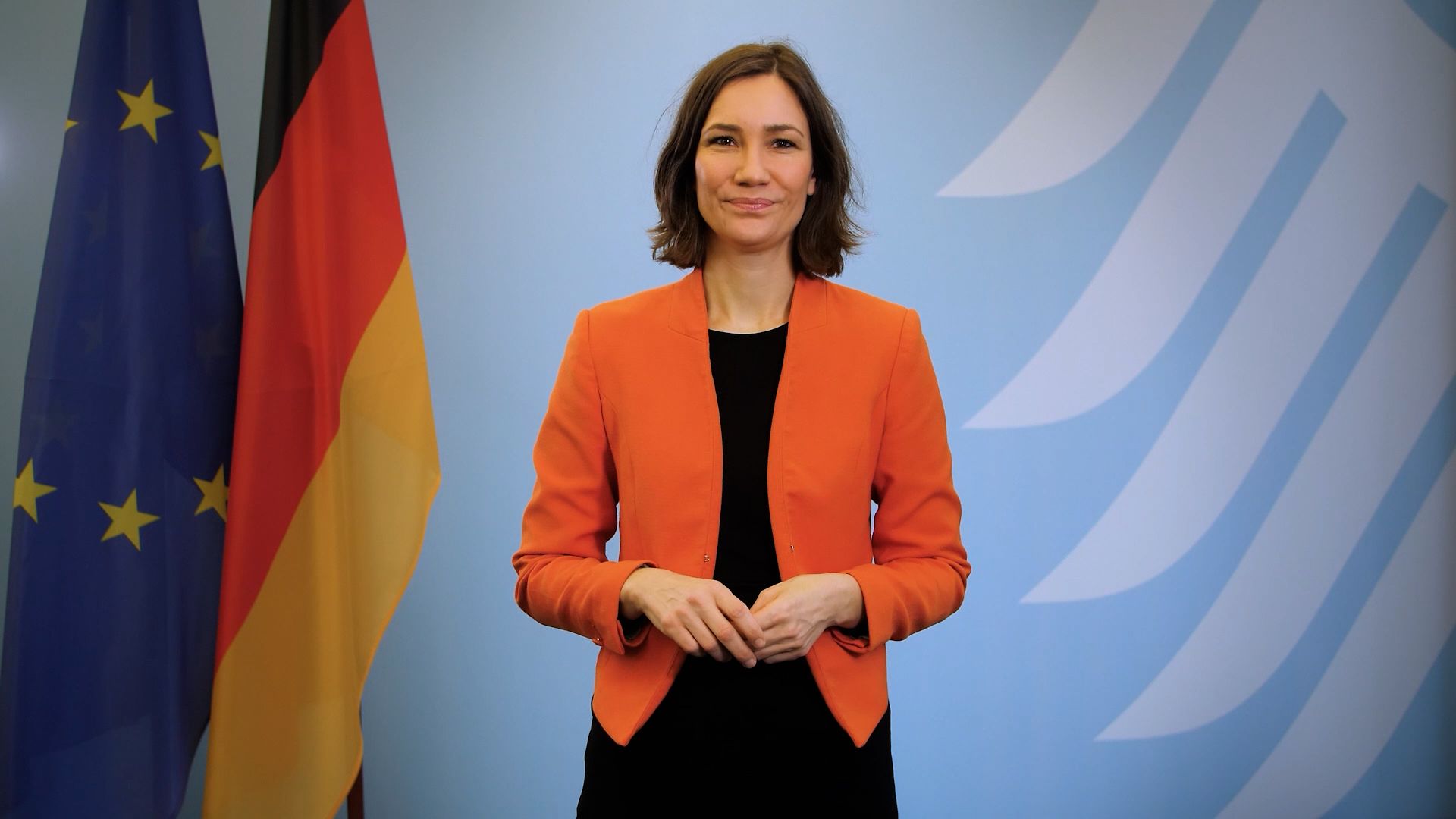 Bundesgleichstellungsministerin Anne Spiegel steht vor der deutschen und europäischen Fahne