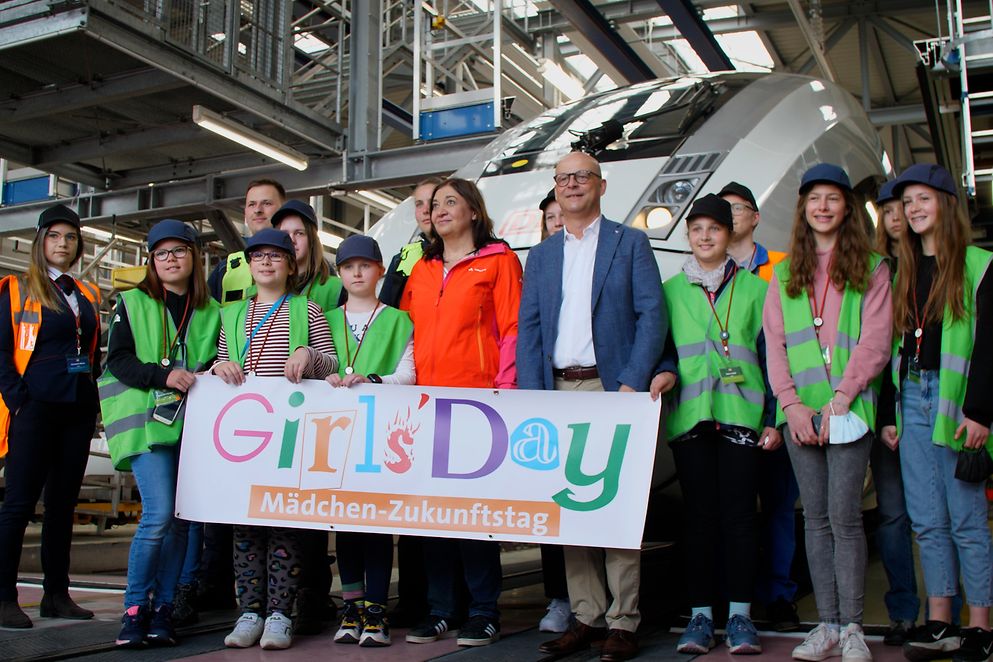 Ekin Deligöz steht mit jungen Frauen vor einem ICE. Sie halten ein Transparent vom Girls'Day