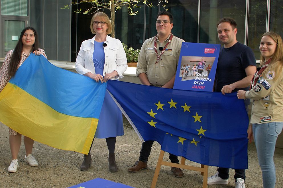 Lisa Paus und vier Jugendvertreterinnen und -vertreter halten eine ukrainische Flagge und die EU-Flagge 