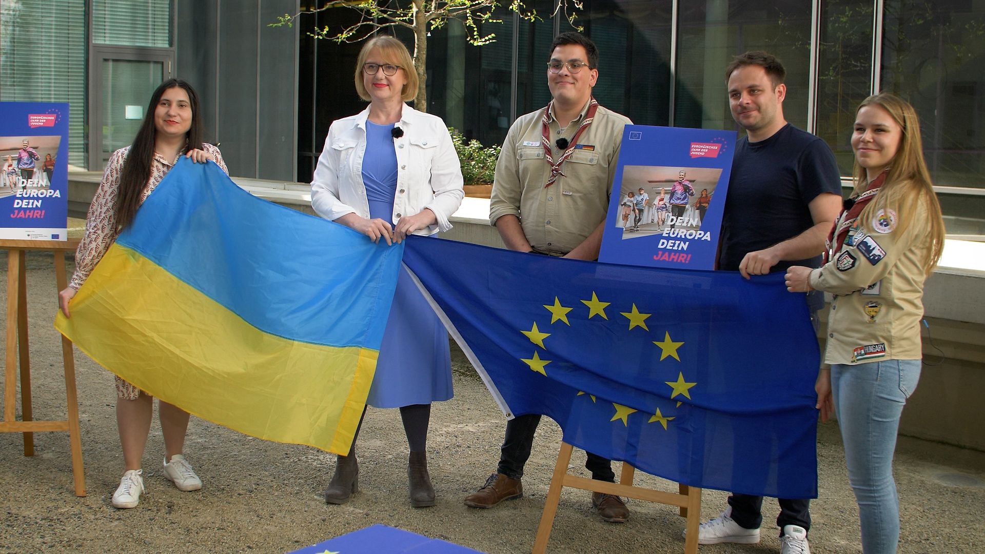 Lisa Paus und vier Jugendvertreterinnen und -vertreter halten eine ukrainische Flagge und die EU-Flagge 