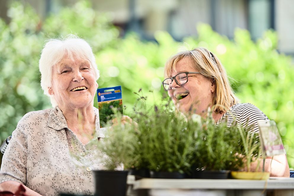 Zwei ältere Frauen unterhalten sich lachend auf dem Balkon