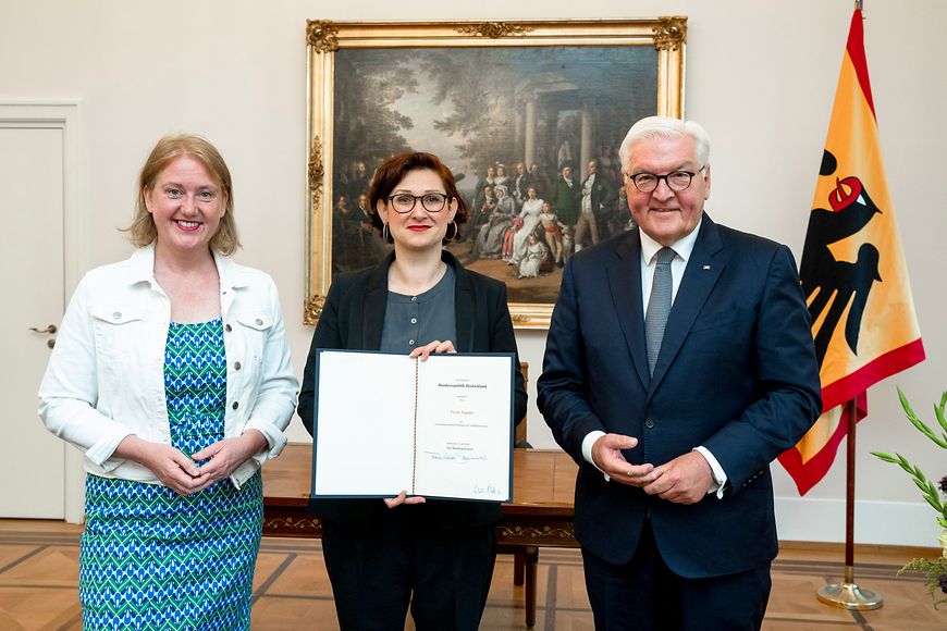 Ferda Ataman zeigt ihre Ernennungsurkunde, die sie von Frank-Walter Steinmeier erhalten hat - im Beisein von Lisa Paus