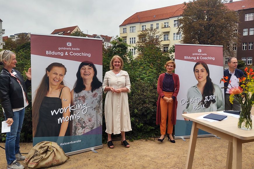 Lisa Paus und Katja Kipping stehen vor zwei Plakatmotiven