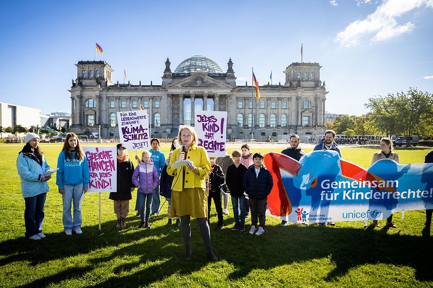 Lisa Paus mit Kindern und Jugendlichen auf der Wiese vor dem Reichtstagsgebäude