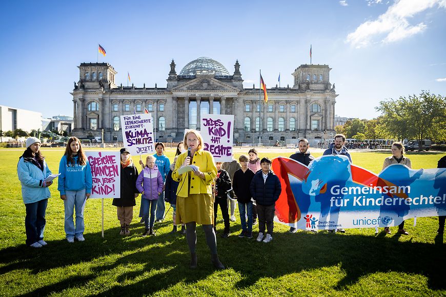 Lisa Paus mit Kindern und Jugendlichen auf der Wiese vor dem Reichtstagsgebäude