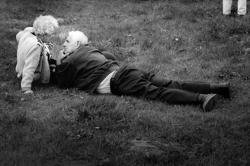 Ein älteres Paar liegt im Gras
