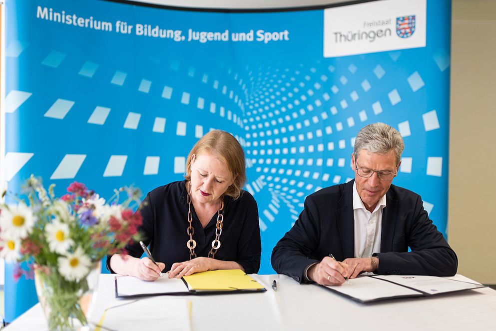 Lisa Paus unterzeichnet mit Helmut Holter die Vereinbarung