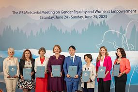 Die Gleichstellungsministerinnen und -minister der G7-Staaten halten die gemeinsame Erklärung in Händen