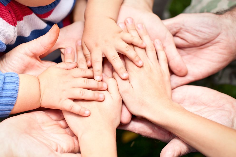 Hände von Kindern und Erwachsenen liegen ineinander