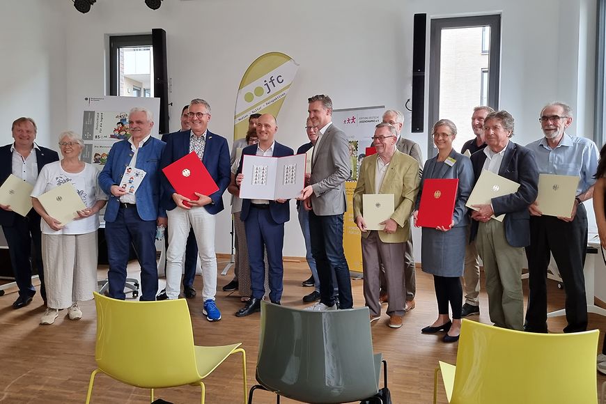 Sven Lehmann steht in einer Gruppe und zeigt die neuen Jugendmarken