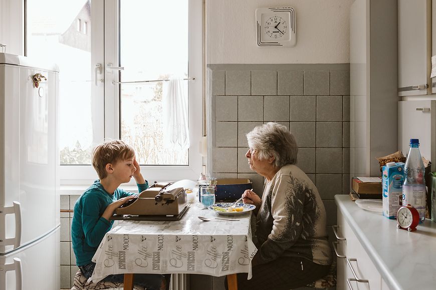 Ein Junge sitzt mit einer älteren Frau in der Küche