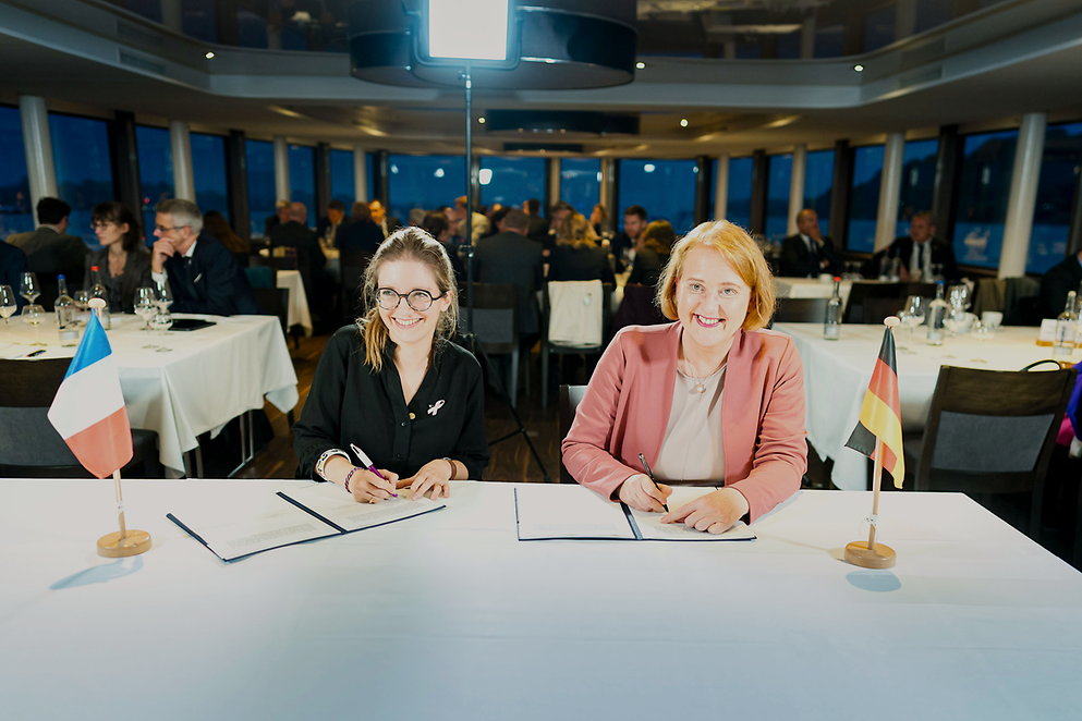 Die französische Ministerin Aurore Bergé und Lisa Paus, Bundesjugendministerin, sitzen gemeinsam an einem Tisch. 