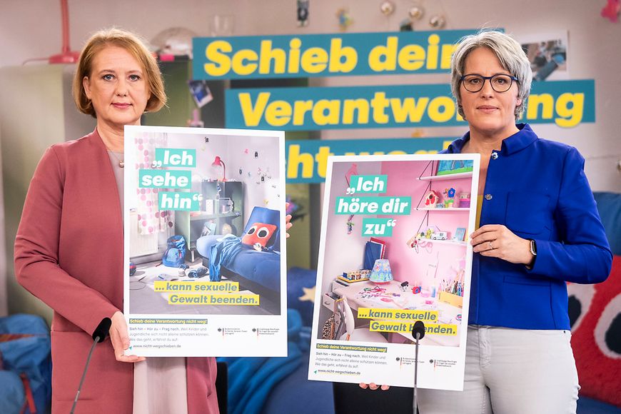 Lisa Paus und Kerstin Claus halten jeweils ein Plakat in den Händen.