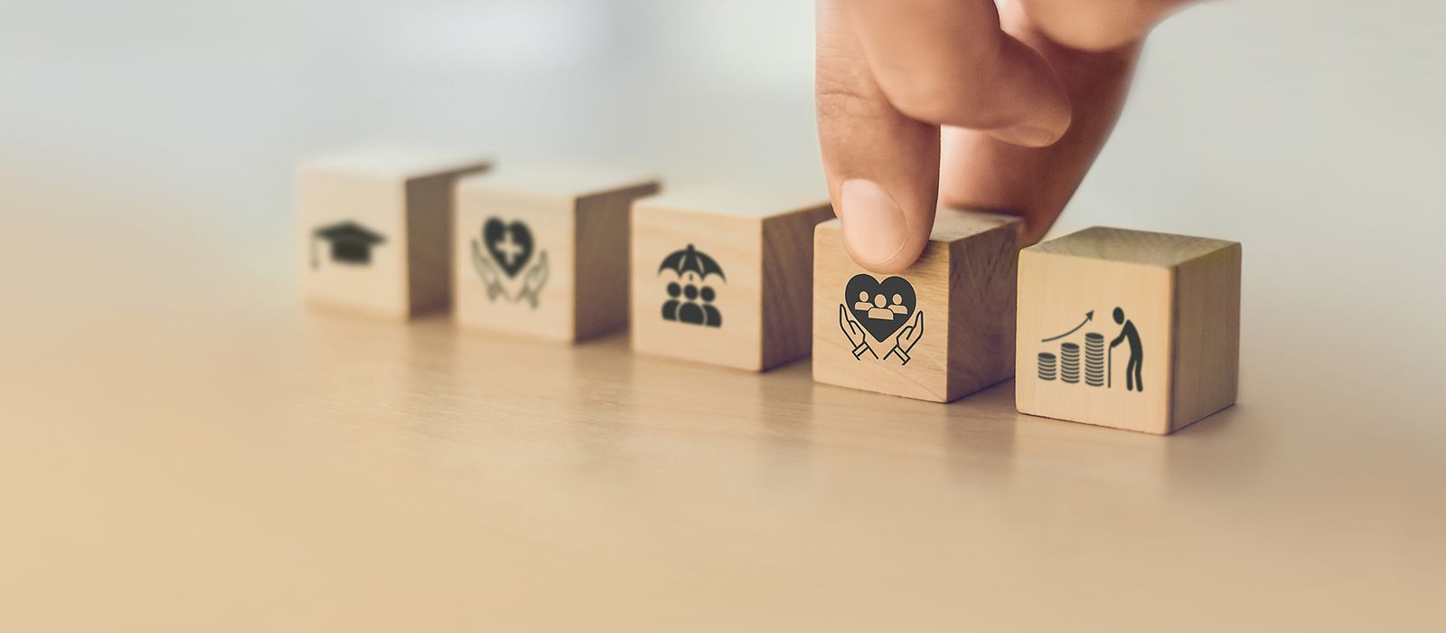 5 Holzwürfel mit verschiedenen gesellschaftsbezogenen Symbolen in einer Reihe