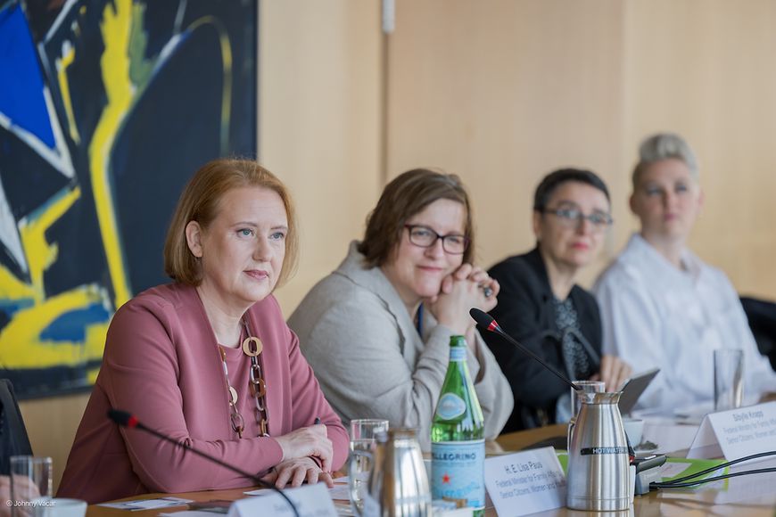 Lisa Paus sitzt mit anderen Teilnehmenden an einem Tisch