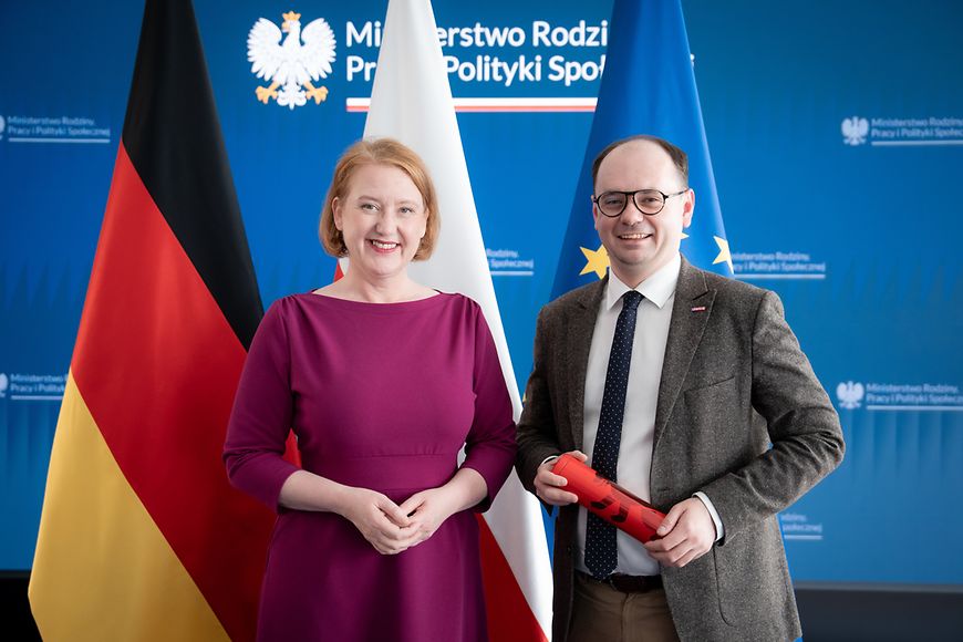 Lisa Paus und Sebastian Gajewski stehen vor der deutschen, polnischen und EU-Flagge 