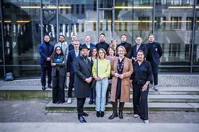 Lisa Paus mit einer Gruppe von Leuten vor einer Fensterfront