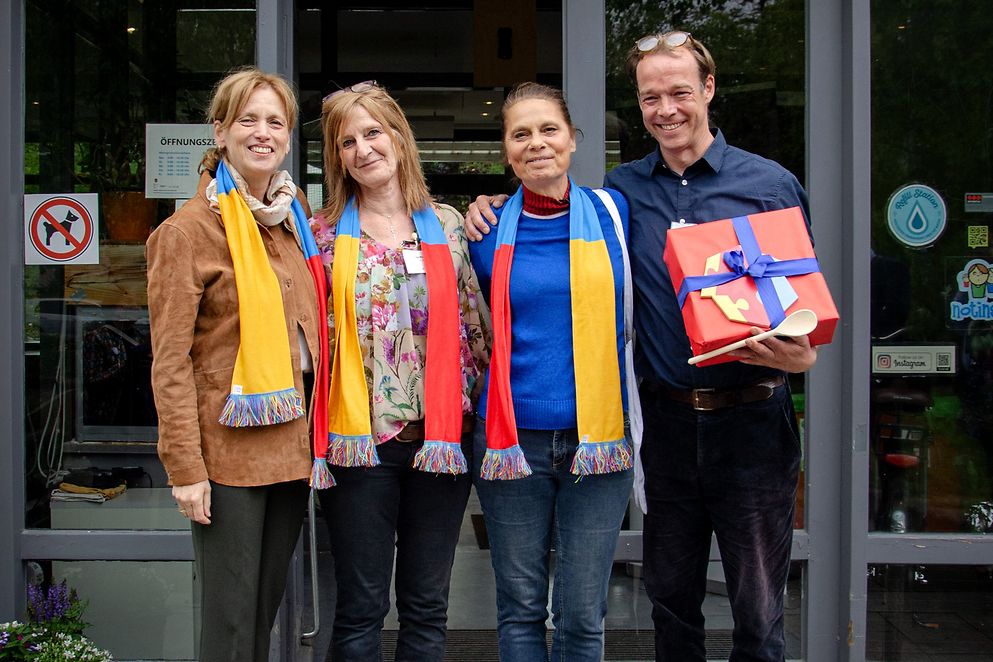 Bundesministerin Karin Prien mit Sarah Wiener und zwei weiteren menschen vor der Eingangstür eines Mehrgenerationenhauses