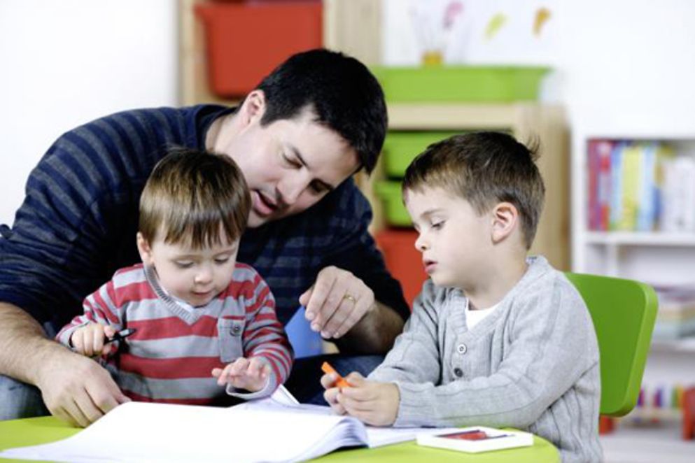Ein Vater sieht sich mit seinen beiden Kleinkindern ein Buch an, Bildnachweis: lostinbids
