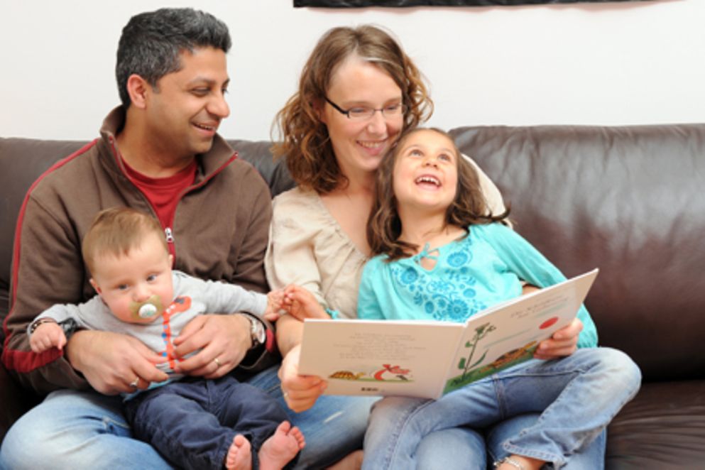 Eltern sehen sich mit Kindern ein Bilderbuch an. Bildnachweis: BMFSFJ / Meike Gronau