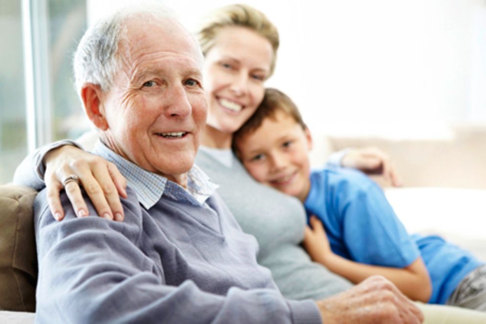 Ein älterer Mann, seine Tochter und sein Enkelsohn sitzen auf einem Sofa. Bildquelle: iStockphoto / Yuri Arcurs