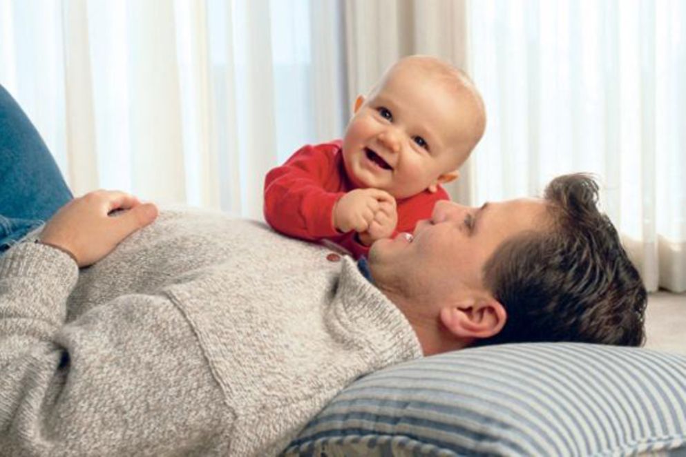 Ein Vater spielt mit seinem Baby auf dem Fußboden, Bildnachweis: istock
