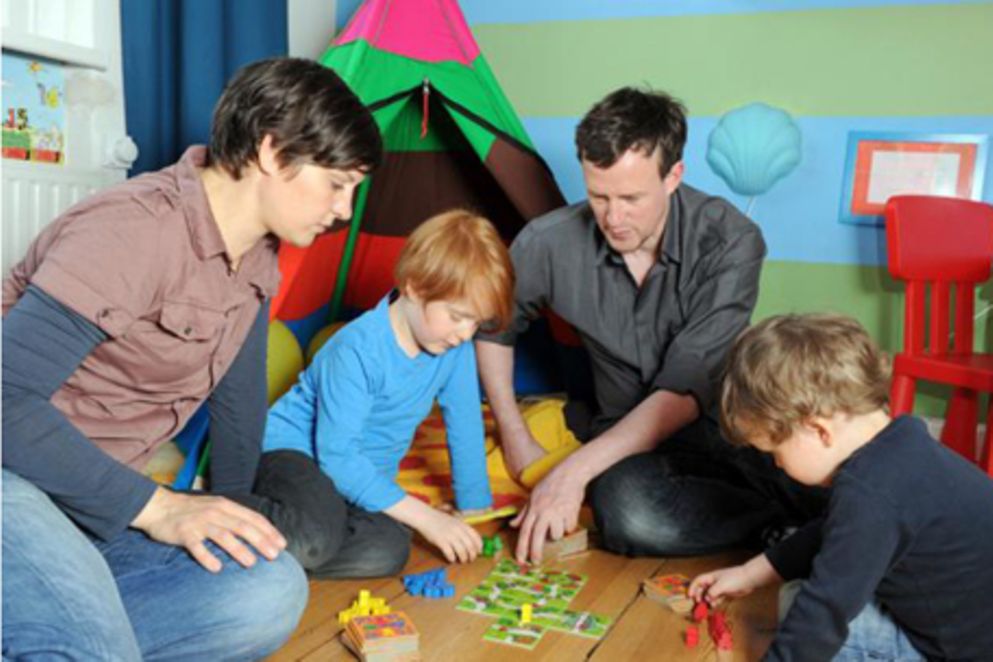 Eltern spielen mit ihrer Tochter und ihrem Sohn im Spielzimmer. Bildquelle: BMFSFJ