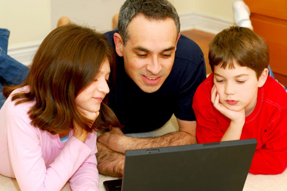 Vater gemeinsam mit seiner Tochter und seinem Sohn vor einem Laptop. Bildquelle: istockphoto.com