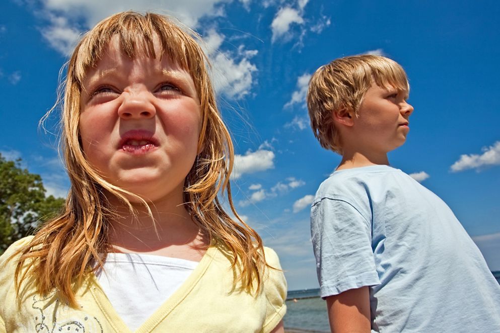 Schwester und Bruder stehen, voneinander abgewendet und verstritten, am Strand. Bildnachweis: Fotolia