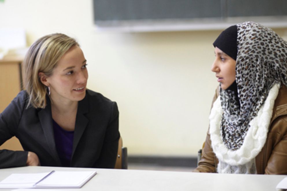 Die Familienministerin in einem Klassenraum im Gespräch mit einer Schülerin. Bildnachweis: BMFSFJ / Laurence Chaperon