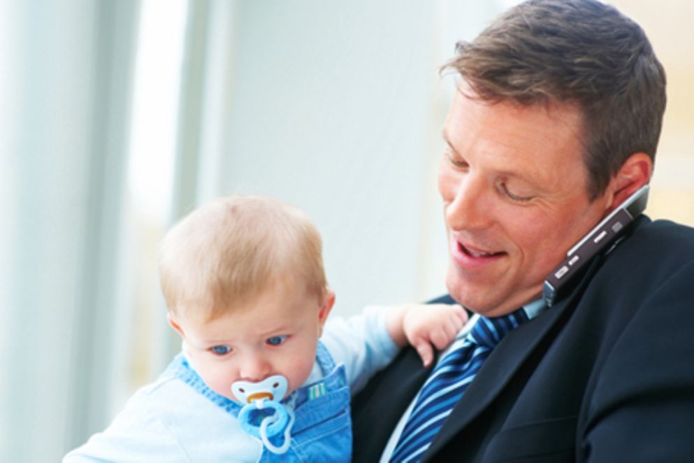 Ein Vater hält sein Kind auf dem Arm, während er geschäftlich telefonieren muss. Bildquelle: iStockphoto