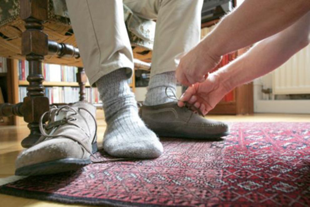Eine Frau bindet einem alten Mann die Schuhe zu, Bildnachweis: BMFSFJ