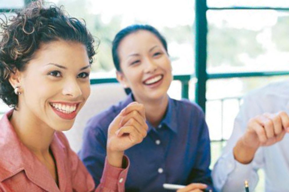 Zwei Frauen sitzen an einem Konferenztisch und lachen, Bildnachweis: BMFSFJ