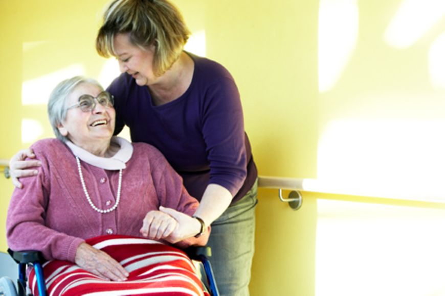 Eine Pflegerin und eine ältere Frau im Rollstuhl