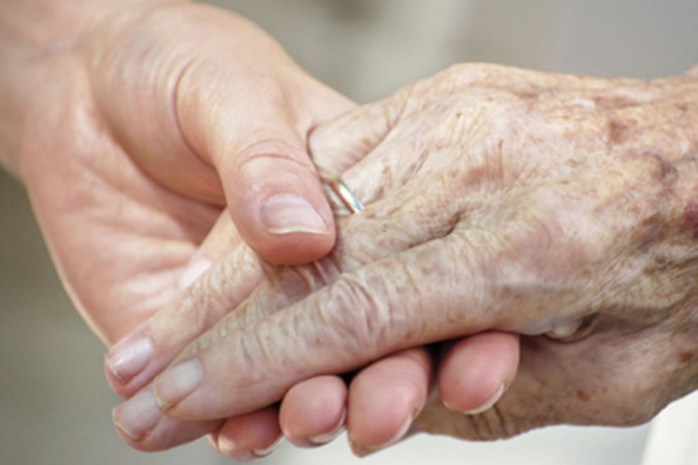 Die Hand einer jüngeren Frau hält die Hand einer älteren Frau.