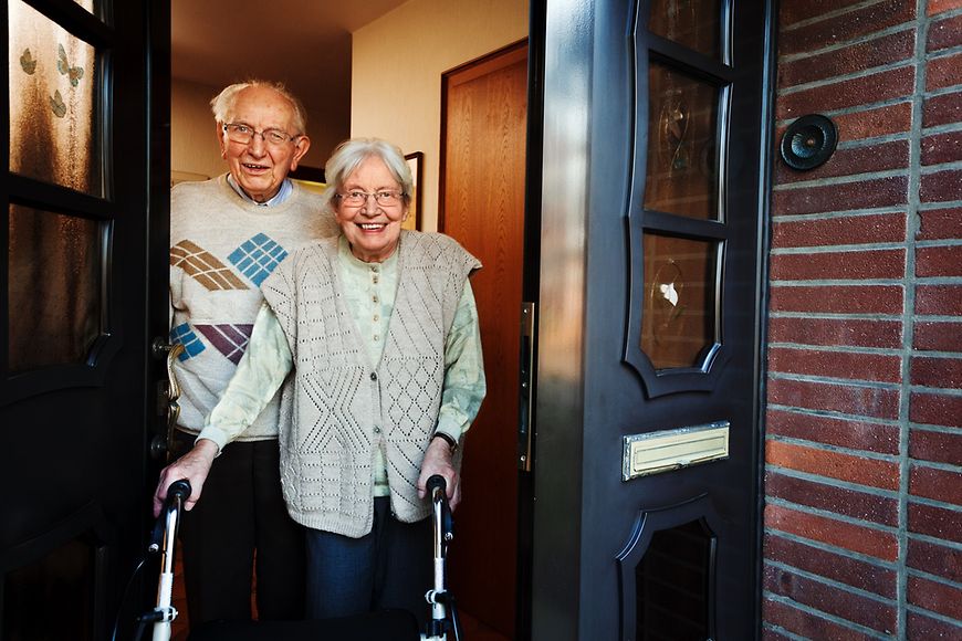 Ein älterer Mann und eine ältere Frau öffnen die Tür zu ihrem Haus