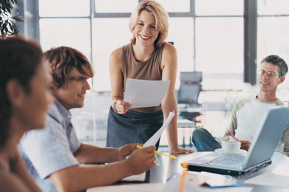 Frauen und Männer sitzen am Tisch und arbeiten. Bildnachweis: BMFSFJ