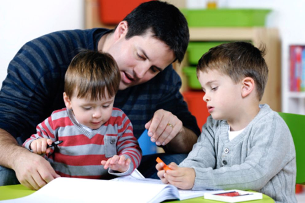 Ein Erzieher spielt mit zwei Jungen in einer Kindertagesstätte. Bildnachweis: lostinbids