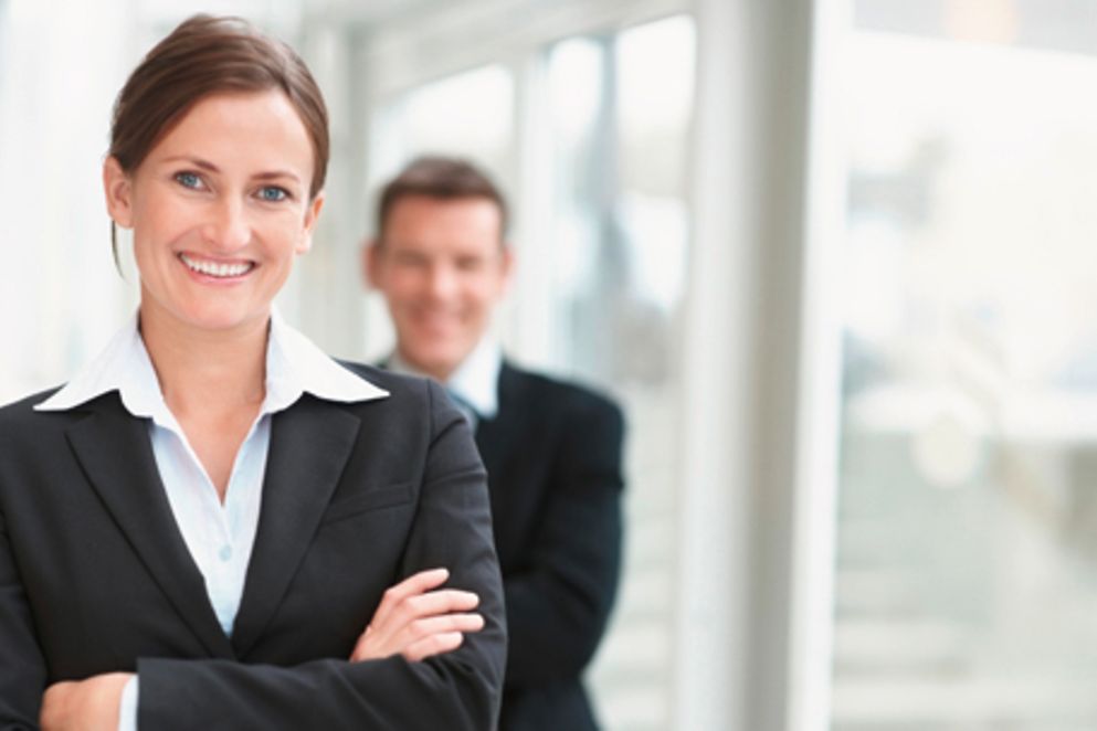 Eine Frau blickt in die Kamera, ein Mann steht im Hintergrund. Bildquelle: Yuri Arcurs / shutterstock.com
